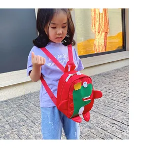Cute cartoon dinosaur children backpack detail, red nylon fabric with green dinosaur plush decor.