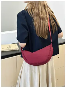 Detailed view of the stylish red crescent dumpling bag, versatile shoulder and crossbody design.