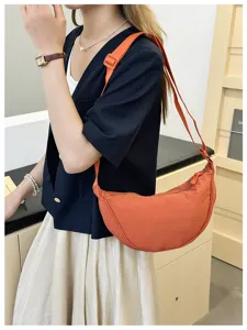 Detailed lifestyle view of orange crescent shoulder bag worn by model, showing style.