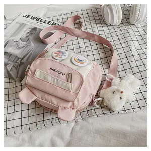 Cute pink nylon crossbody bag detail, sweet bear ears design, plush pendant, flat lay.