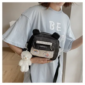 Cute nylon crossbody bag for women with bear ears and plush pendant, sweet casual shoulder bag.
