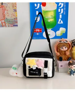 Close-up detail of the black and white crossbody bag with cute plush star charms and front pocket.