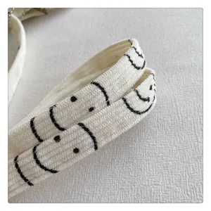 Detailed shot of casual bag strap with cute black smiley design, durable fabric texture.