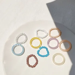 Detail view of multi-color resin and beaded elastic rings, minimalist women fashion jewelry.