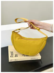 Detail view of a stylish yellow nylon crescent dumpling bag with adjustable shoulder strap.