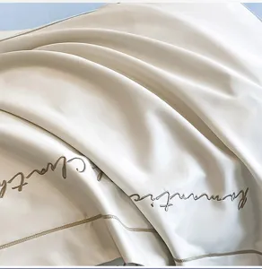 Detalle de sábana de lujo de algodón de alta densidad con elegante bordado cursivo.