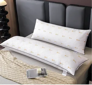 Detailed view of long couple bed pillow with white quilted fabric and gold love embroidery.
