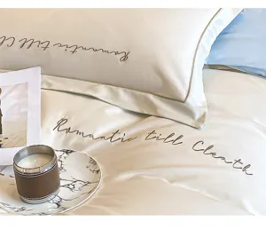 Detalle de juego de ropa de cama de algodón bordado de lujo, tela suave con elegante tipografía.