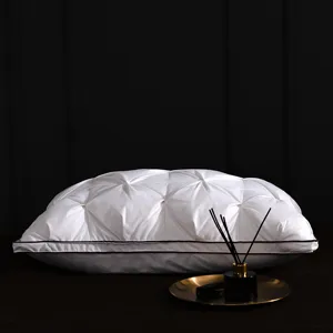 Detail view of white luxury down pillow with elegant tufted pleats and dark piping trim.