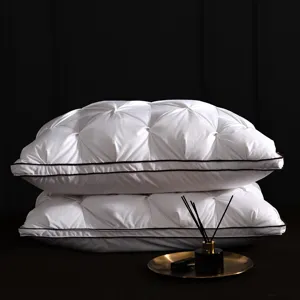Premium white goose down pillow with tufted pinched design and elegant dark piping detail.