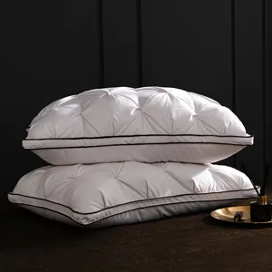 Detailed view of luxury white goose down pillow, quilted pleated design with dark piping.