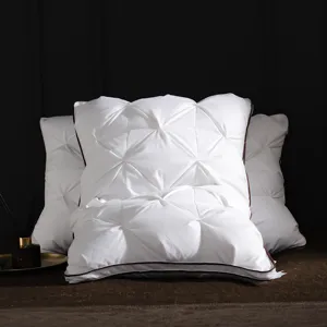Detailed view of luxury white down pillow with pin-pinch pleated texture and elegant dark piping.