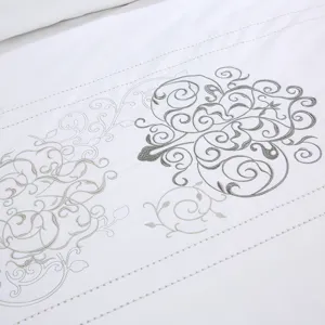 White embroidered cotton hotel bedding set with 60s sateen luxury duvet cover detail.