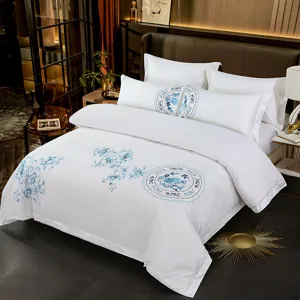 Detailed view of luxury white cotton bedding set with blue embroidery, 60s satin hotel style.