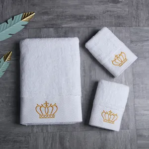 Conjunto de toallas de baño de algodón blanco para hotel con elegante bordado de corona dorada.