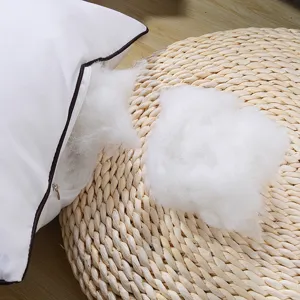 Detailopname van witte kussenvulling met pluizige vulling en netjes donkere bies.