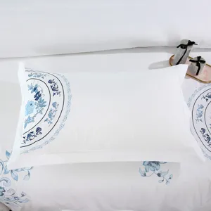 Detailed close-up shot of white cotton satin pillowcase with elegant blue floral embroidery.
