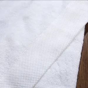 Close up detail of white cotton hotel towel with soft dobby border texture fabric.