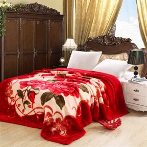 Cozy red floral raschel blanket shown in a warm bedroom setting, perfect for winter bedding.