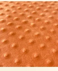 Nahaufnahme des weichen orangen Minky-Noppen-Stoffes mit 3D-Prägung für Textilien.