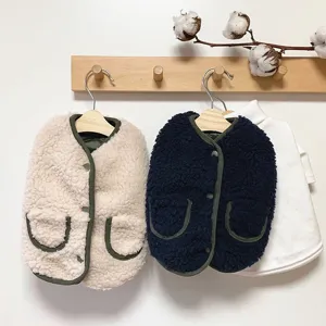 Detail view of cozy fleece pet vest hanging on wooden hook against clean white wall surface.