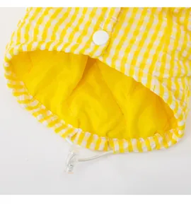 Yellow and white checkered pet winter coat detail, quilted lining with snap button.
