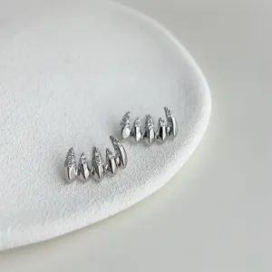 Detailed shot of unique claw-shaped micro-set zircon silver earrings, showcasing fine texture.