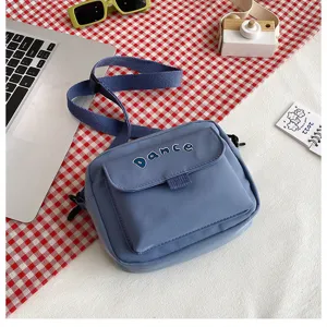 Close-up detail of the blue nylon crossbody bag featuring front pocket and adjustable strap.