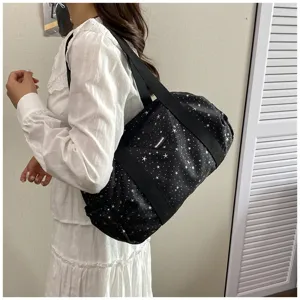 Vue détaillée du sac de voyage noir décontracté à motif d'étoiles avec bandoulière et étiquette.