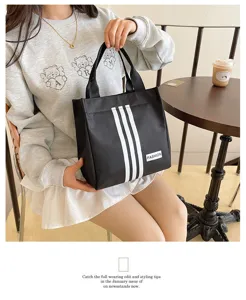 Bolso tote negro de lona con tres rayas elegantes y asas resistentes para el uso diario y trabajo.
