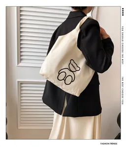Close-up detail of the canvas tote bag with cute bear print and shoulder strap design.