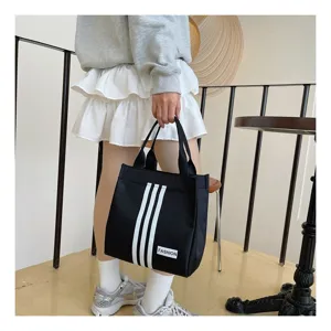 Bolso tote de lona negra con tres rayas blancas y etiqueta para uso diario casual.