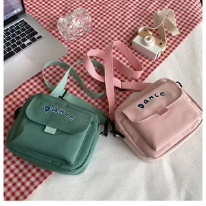 Detailed shot of cute solid color nylon cross-body bag with flap and letter print design.