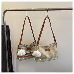 Summer woven straw shoulder bag detail view featuring cute cloud pendant and brown strap.