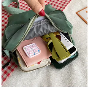 Green nylon crossbody bag capacity detail showing interior space with multiple daily items.