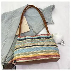 Detail shot of the colorful woven straw handbag with brown PU leather handles and cute charm.