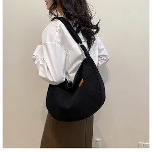 Detailed view of the black corduroy shoulder slouchy tote bag worn by model, casual style.
