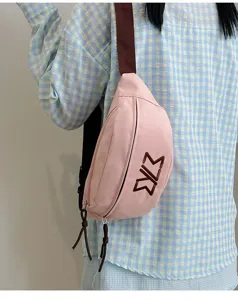 Detailansicht der stylischen pinken Brusttasche mit braunem Gurt und gesticktem Logo.