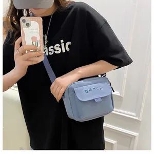 Close-up detail of the casual light blue nylon crossbody bag with letter embroidery.