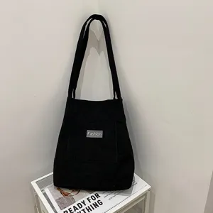 Casual black corduroy tote bag for women, vintage shoulder bag with front pocket design.