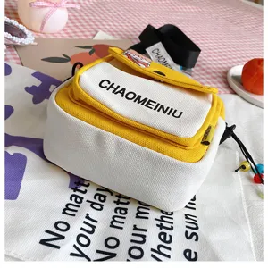 Dettaglio borsa a tracolla in tela che mostra design bicolore giallo e bianco.