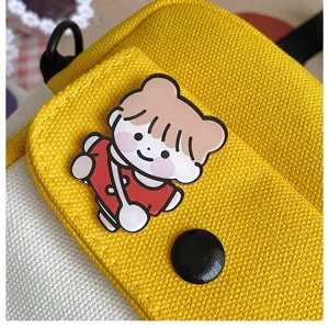 Primo piano dettagliato della tasca anteriore della borsa a tracolla in tela con badge.