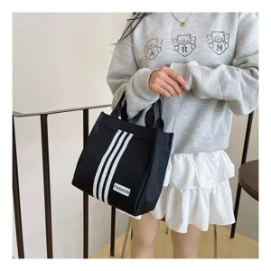 Bolso tote de lona negra con tres franjas verticales y asas superiores para uso diario.