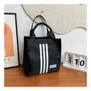 Bolso de mano negro de lona con tres rayas clasicas y etiqueta de moda para uso diario.
