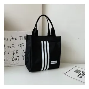 Bolso tote de lona negra con elegantes tres rayas blancas y asas prácticas para uso diario.