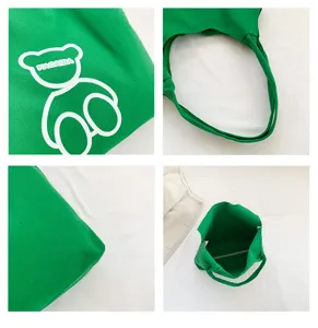 Green canvas tote bag detail view showing bear print, durable strap, and large capacity.