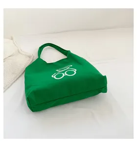 Green canvas tote bag detail view, casual shoulder bag with cute glasses print, daily use.