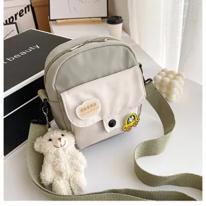 Close-up of a cute canvas crossbody bag with bear pendant and color-blocking design detail.