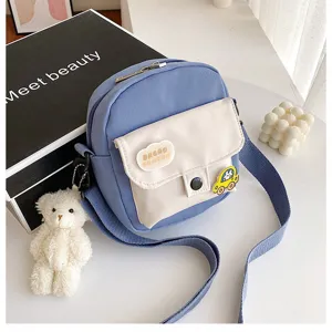 Close-up of cute blue canvas crossbody bag with white pocket, adorable plush bear details.