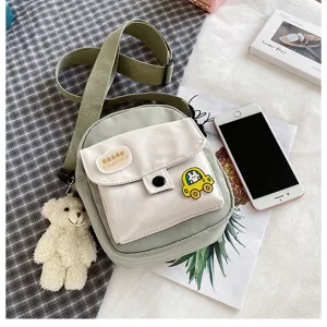Detailed view of the cute canvas crossbody bag with small bear pendant and stylish patch.